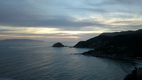 Aerial Hyper Lapse Cloudy Sunset over rock coast with island in background Stock Footage 89486257