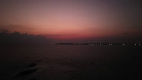 Aerial hyperlapse captures a lighthouse beacon illuminating waves against rocks Stock Footage 265155015