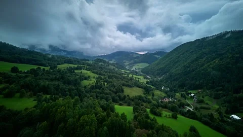 Aerial hyperlapse of green valley with forested hills and dramatic cloudy sky Video stock 317224863