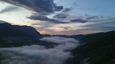 Aerial hyperlapse of mountain town covered by fog at sunset Stock Footage 274780202