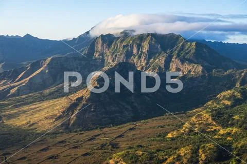 Aerial image of the lush mountains surrounding Oahu being illuminated by late af Stock Photos