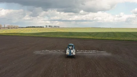 Aerial image of tractor spraying soil and young crop in springtime in field. Stock Footage 131308965