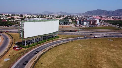 Aerial of a large empty billboard placed at the on-ramp of a busy highway in Видео 332817224