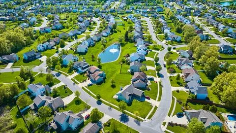 Aerial large suburbs of multiple colored houses with nearby pond with water Stockfoto's