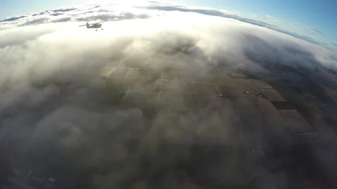 Aerial light plane flying in clouds over orchards and sun lit clouds Stock Footage 237828597