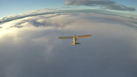 Aerial light plane flying over clouds and turning away in sunset Stock Footage 237883261