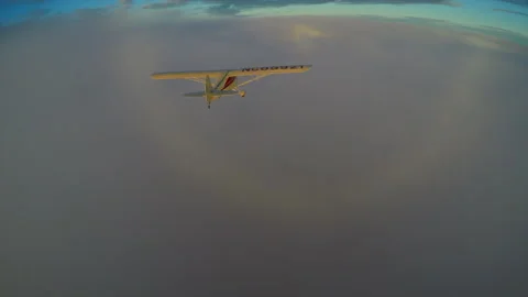 Aerial light  plane flying over clouds into circular rainbow sunset Stock Footage 237971344