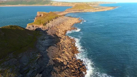 Aerial linear shot over Worms Head island in Rhossili &amp; cliffs by Atlantic Ocean Stock Footage 165455491