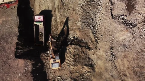 Aerial loading operation of excavator loading truck filmed from above at day Stock Footage 343952492
