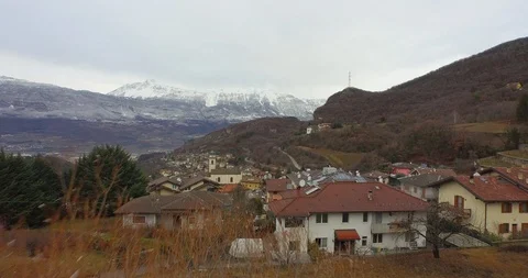 Aerial of local settlements on hilly terrain, snowcapped mountains in background Stock Footage 89977282