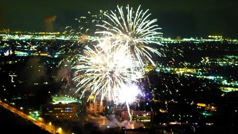 Aerial Lockdown Shot Of Fireworks Exploding Over Buildings In Illuminated City Stock Footage 255408678
