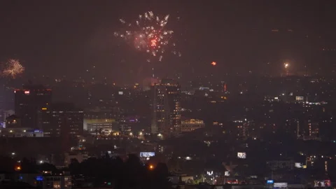 Aerial Lockdown Shot Of Glowing Fireworks Bursting In City Against Sky At Night Stock Footage 264356923