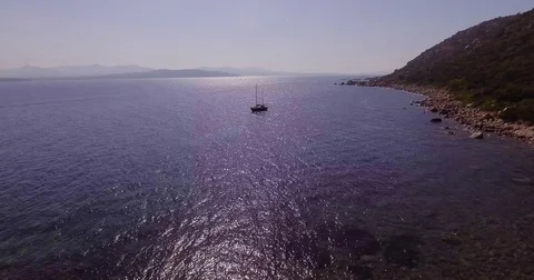 Aerial, a lonely sailing ship in backlight in a beautiful bay with crystallin Stock Footage 84258067