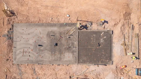 Aerial long shot of construction workers building concrete foundation of house Stock Footage 201160106
