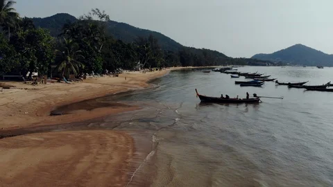 Aerial: A longboat unloading passengers on the beach of an island Stock Footage 100454861