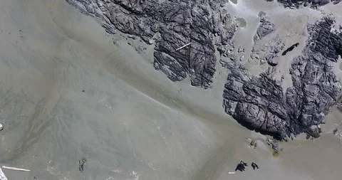 Aerial look-down Push Shot of beach turning to waves breaking on rocks Stock Footage 106848986