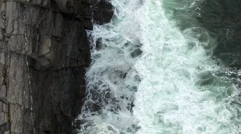 Aerial looking down on breaking waves against rocks Stock Footage 56534175