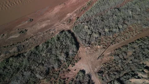 Aerial looking down on power lines along muddy Virgin river bank in Nevada Stock Footage 265108779