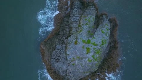 Aerial: looking down on waves washing over a rocky outcrop Stock Footage 203412686
