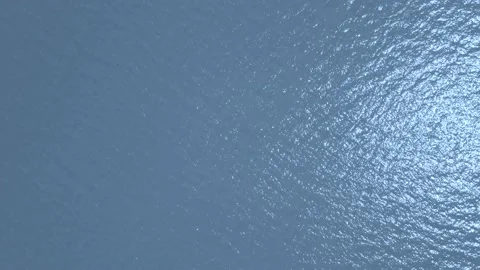 Aerial looking straight down and flying quickly forward over a large blue lake.  Stock Footage 156763018