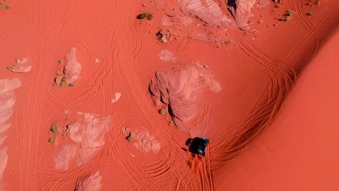 Aerial-Looking straight down on small off road vehicle in orange sand Stock Footage 117623355