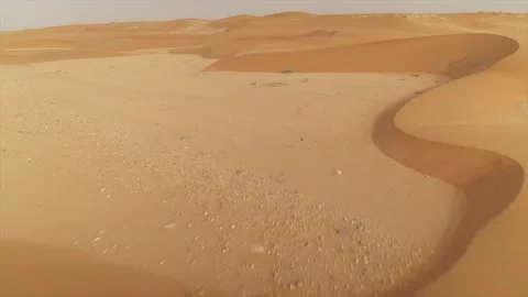 Aerial low altitude drone flight over flat sand towards desert dunes in El Stock Footage 336292245