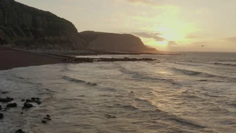 Aerial low angle fly over beautiful Hastings beach with rocky shore and dramatic 스톡 동영상 251034886