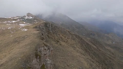 Aerial low flight at top of the mountain into the clouds while snowing Stock Footage 215916477