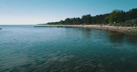 Aerial low-level pass over the shallow water of the sea bay on a sunny day Stock Footage 146701191
