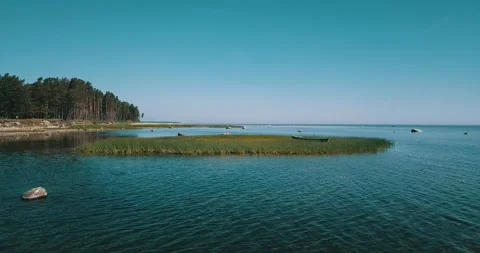 Aerial low-level pass over the shallow water of the sea bay on a sunny day Stock Footage 146701300