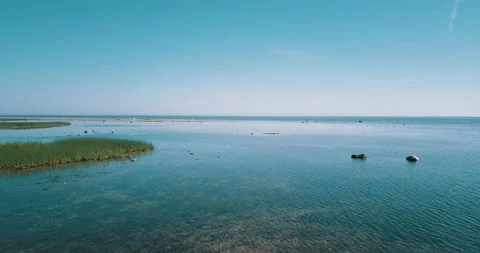 Aerial low-level pass over the shallow water of the sea bay on a sunny day Stock Footage 146701366