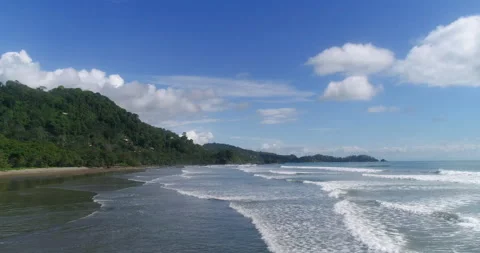 Aerial Low Over Beach Surf Waves Next To Jungle Beach On A Sunny Blue Cloud Day Stock Footage
