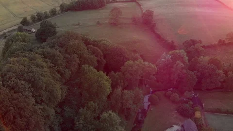 Aerial, low pull back, Cotswolds village and church, sun flares Stock Footage 99158338