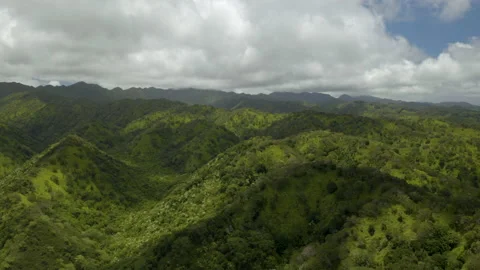 Aerial lush green mountain range in Hawaii with moving cloud shadows Видео 136561374