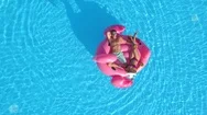 Aerial: Man And Woman In Swimsuits Laying On Fun Pink Inflatable Flamingo Float Stock Footage