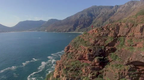 Aerial of Man on Cliff Looking out at Ocean, Chapmans Peak, Cape Town Video stock 60115033
