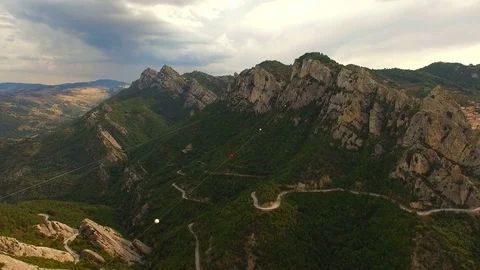 Aerial. A man flies between two mountain peaks over a stunning valley Stock Footage 71842652