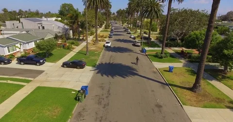 Aerial of man riding bicycle on a residential street on a sunny day Stock Footage 81532053