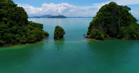 Aerial: A man swims on a sup board in the sea near the islands. Stock Footage