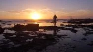 Aerial: Man Walking Into The Ocean At Sunrise Stock Footage