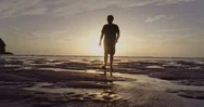 Aerial Man Walking Into The Sunset. Piha, Auckland, New Zealand Stock Footage