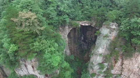 AERIAL OF MASSIVE CAVE ON STEEP CLIFF SIDE IN AVATAR ZHANGJIAJIE MOUNTAINS CHINA Stock Footage 65210010