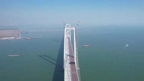Aerial a massive suspension bridge under construction over calm coastal waters Stock Footage 342279959