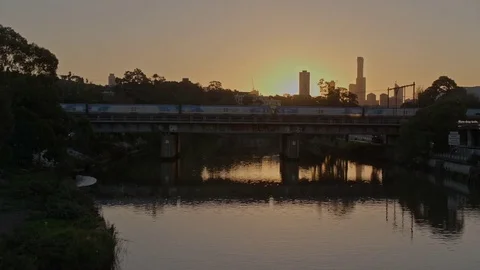 Aerial of Melbourne skyline and train passing over the river Stock Footage 81001736