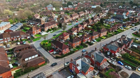 Aerial mid angle quick panning shot over English suburb village town in spring Stock Footage 332373154