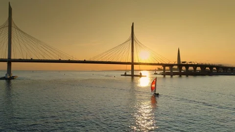 Aerial modern cable-stayed bridge Petersburg cityscape sunset bay river Sailboat Stock Footage 128749256