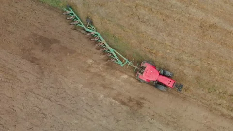 Aerial: modern tractor with a multi-plow plow that cultivates the soil for Stock Footage 143889631