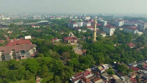 Aerial mosque minaret overlooking dense green Yogyakarta city neighborhood Stock Footage 342581650