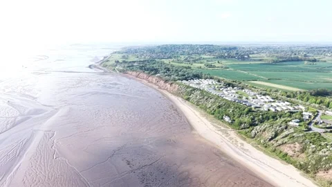 Aerial motion along beach edge with smooth water patterns and natural summer Stock Footage 337307493