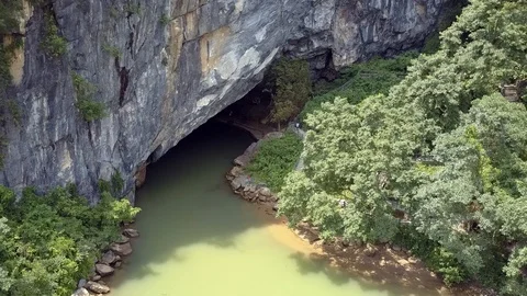 Aerial motion to cave gate and calm river in national park Vidéo 106049022